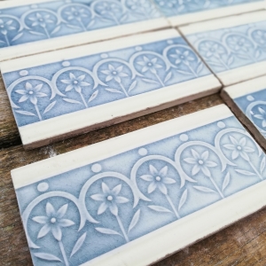 38 stuks antieke randtegels 15x7,5cm, zacht geel afgebiesd, warm grijsblauwe bloem